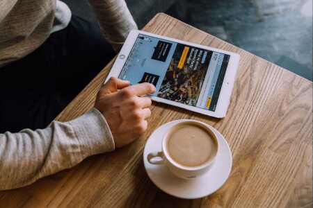 Na stole tablet z&nbsp;otwartą stroną rybka.rybnik.eu, obok filiżanka kawy
