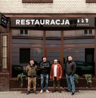 Fasada restauracji Szeroka, na jej tle pracownicy