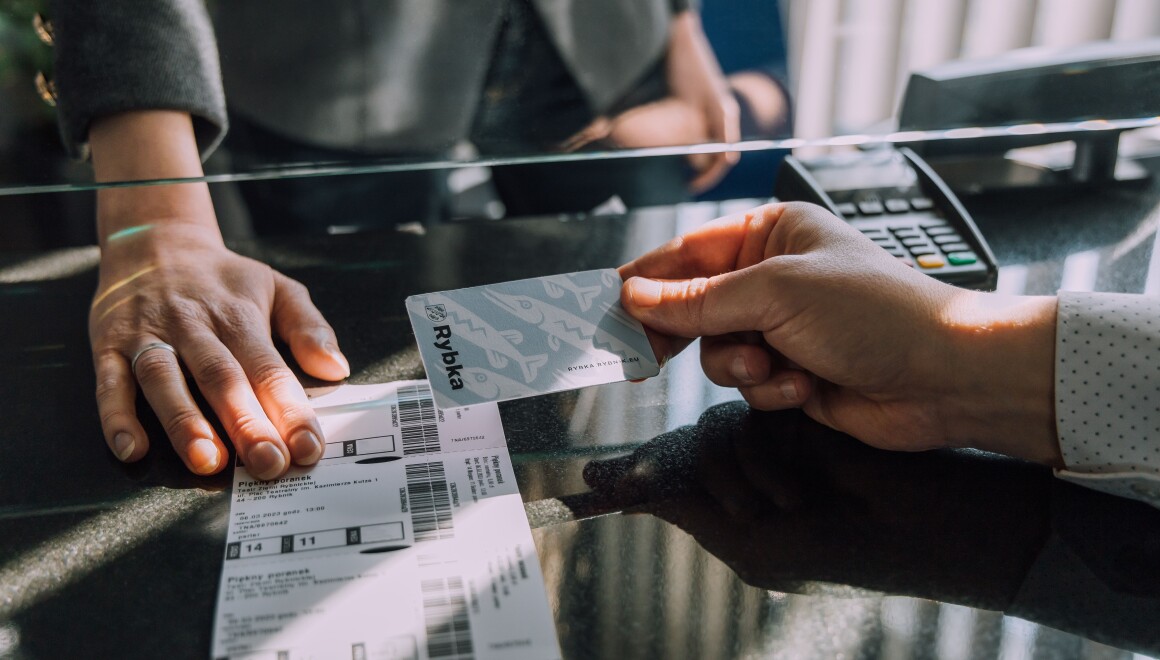 Dłoń trzymająca Karte Rybka w&nbsp;okienku biletowym 