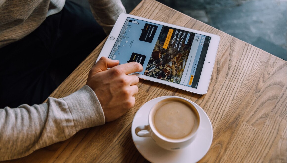 Na stole tablet z&nbsp;otwartą stroną rybka.rybnik.eu, obok filiżanka kawy