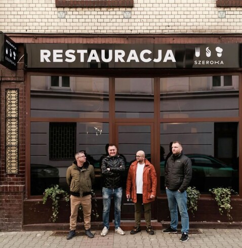 Fasada restauracji Szeroka, na jej tle pracownicy